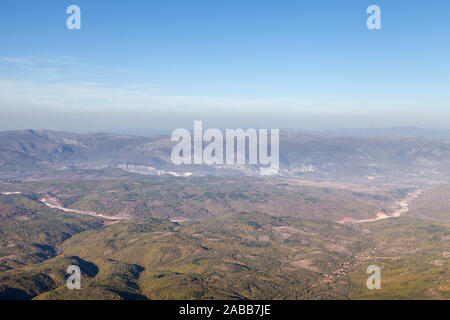 Vue de dessus d'une route sinueuse route allant à travers les vallées et montagnes en arrière-plan avec la forêt et ciel bleu Banque D'Images