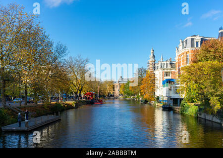 Amsterdam/Pays-Bas - 8 novembre 2019 : Bateaux dans les canaux d'Amsterdam, couleurs d'automne et ciel bleu Banque D'Images