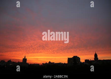 Beau Soleil colorés ciel au-dessus de la skyline et toits de la ville, avec des bâtiments en ossature, Malaga, Andalousie, Espagne du Sud. Banque D'Images