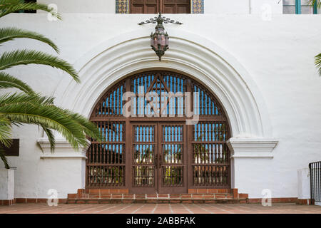 Grande porte en bois ouvragé dans une entrée voûtée d'un bâtiment de style espagnol blanc historique à Santa Barbara, Californie, USA Banque D'Images