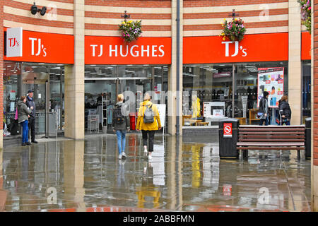 Scène de rue par temps humide et la pluie qui tombe sur des réflexions de la chaussée de marche de shoppers TJ Hughes retail shop business dans le comté de Durham Durham England UK Banque D'Images