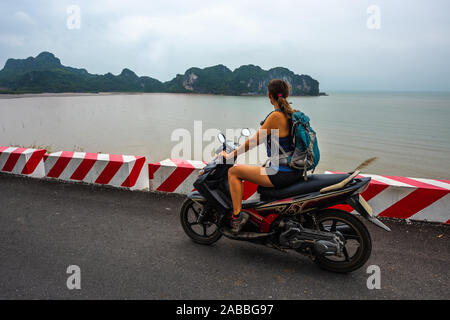 Ile de Cat Ba Vietnam'Girl sur un scooter sac à dos porter admire une vue magnifique de la Baie d'Ha Long Banque D'Images