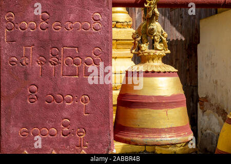 Temple bouddhiste peint avec Bell une prière inscrite en birman script sur un mur qui porte la cloche de Kanne village, la rivière Chindwin, Myanmar (Birmanie) Banque D'Images