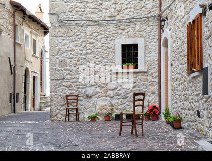 Petite place dans un vieux village avec deux chaises vides en face d'une maison Banque D'Images