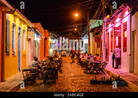 Les touristes assis sur les tables le long de la rue étroite à petite ville Lencois, Bahia, Brésil. Banque D'Images