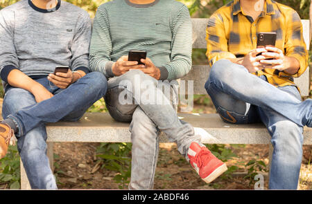 Les jeunes hommes occupés sur mobile alors qu'il était assis sur la table du park - Concept de jeune génération accro au smartphone, de la technologie et de gadgets électroniques - Banque D'Images