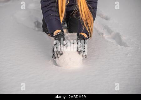 Jeune femme rouler en boule géante pour faire snowman Banque D'Images
