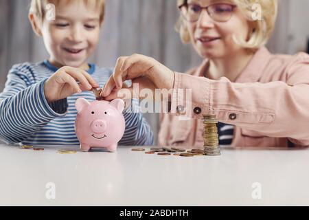 Trois ans enfant assis st la table avec de l'argent et une tirelire Banque D'Images