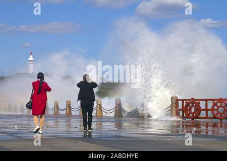 Deux piétons prendre des photos d'énormes vagues provoquées par de puissants coups de froid la rive à Yantai City, Shandong province de Chine orientale, le 14 octobre 201 Banque D'Images