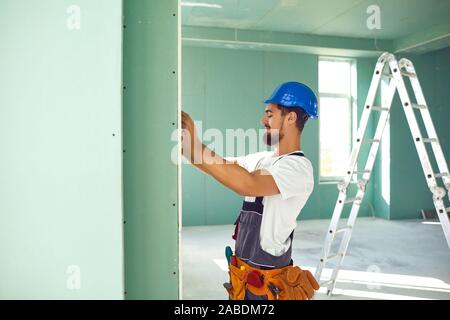 Constructeur travailleur installe des cloisons sèches à une construction de plâtre Banque D'Images