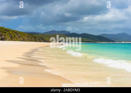 Belle plage tropicale avec mousse blanche mer vague. D'eaux turquoise et de sable blanc de silice de Whitehaven Beach. Queensland, Australie Banque D'Images