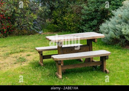 Table de pique-nique en bois et deux bancs en extérieur sur pelouse verte Banque D'Images