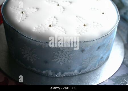 Bleu et blanc élégant gâteau aux fruits de Noël, glaçage blanc sur le dessus et sainte impressions avec des boules d'argent, ruban flocon tout autour du gâteau, et bleu Banque D'Images