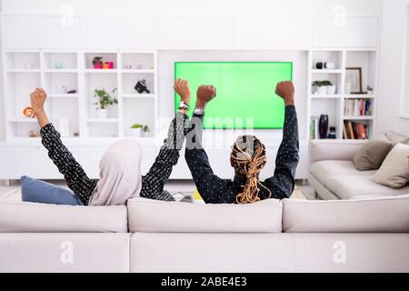 African Couple Watching TV écran vert Chroma Ensemble Femme portant des vêtements hijab islamique Banque D'Images
