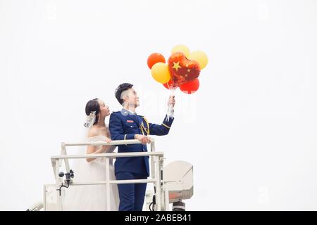 Fireman Jia Jie et sa femme prennent des photos avec l'aide de ses collègues en face d'un camion de lutte contre l'incendie de la ville de Chengdu, dans le sud-ouest de la Chine. Banque D'Images