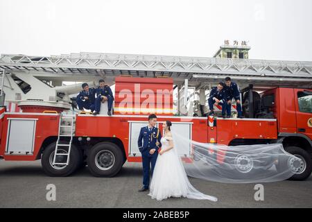 Fireman Jia Jie et sa femme prennent des photos avec l'aide de ses collègues en face d'un camion de lutte contre l'incendie de la ville de Chengdu, dans le sud-ouest de la Chine. Banque D'Images