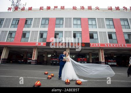 Fireman Jia Jie et sa femme prennent des photos avec l'aide de ses collègues en face d'un camion de lutte contre l'incendie de la ville de Chengdu, dans le sud-ouest de la Chine. Banque D'Images