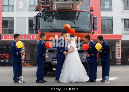 Fireman Jia Jie et sa femme prennent des photos avec l'aide de ses collègues en face d'un camion de lutte contre l'incendie de la ville de Chengdu, dans le sud-ouest de la Chine. Banque D'Images