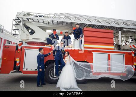 Fireman Jia Jie et sa femme prennent des photos avec l'aide de ses collègues en face d'un camion de lutte contre l'incendie de la ville de Chengdu, dans le sud-ouest de la Chine. Banque D'Images