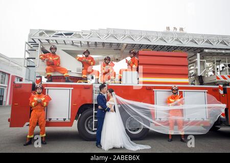 Fireman Jia Jie et sa femme prennent des photos avec l'aide de ses collègues en face d'un camion de lutte contre l'incendie de la ville de Chengdu, dans le sud-ouest de la Chine. Banque D'Images