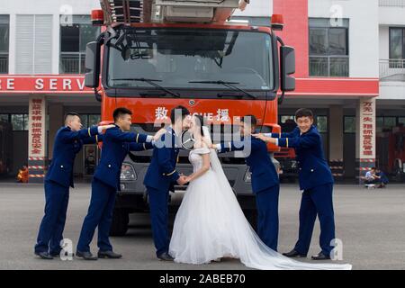 Fireman Jia Jie et sa femme prennent des photos avec l'aide de ses collègues en face d'un camion de lutte contre l'incendie de la ville de Chengdu, dans le sud-ouest de la Chine. Banque D'Images