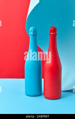 Maison de vacances peint décoratif maquette des bouteilles rouge et bleu sur un fond duotone avec feuille de papier ondulé bleu derrière, copiez l'espace. Banque D'Images