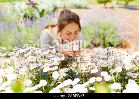 Happy woman smelling fleurs de camomille dans le jardin Banque D'Images