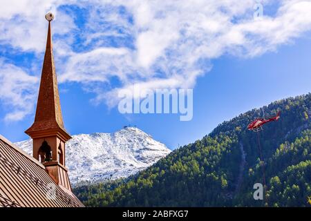 Zermatt, Suisse - le 7 octobre 2019 : l'église anglicane St Pierre, la neige des montagnes et de l'hélicoptère rouge Banque D'Images