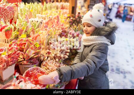 Petite fille de choisir des bonbons au marché de Noël Banque D'Images