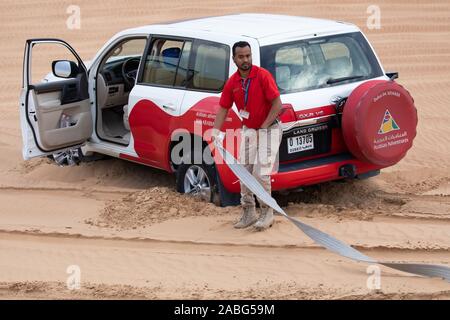 Un 4X4 Land Cruiser permet de tirer un autre Land cruiser qui avait coincé au sommet d'une dune de sable dans le désert du Sahara, Dubaï Banque D'Images