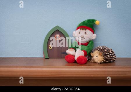 Lutin de Noël assis à côté d'elf porte avec toy hérisson. La tradition d'envoyer Cute Santa's elf de vérifier les enfants juste avant Noël. Banque D'Images