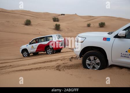 Un 4X4 Land Cruiser permet de tirer un autre Land cruiser qui avait coincé au sommet d'une dune de sable dans le désert du Sahara, Dubaï Banque D'Images