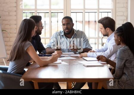 Groupe diversifié de professionnels à l'écoute de african american chef d'équipe. Banque D'Images