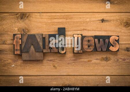 Fake news, une phrase écrite avec la typographie vintage blocks sur fond de bois rustique. Banque D'Images