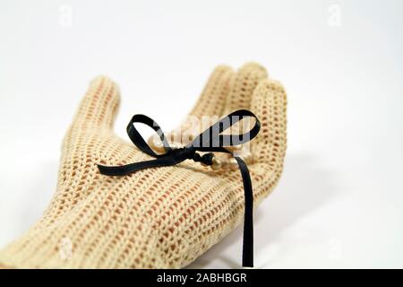 La main avec des gants en crochet vintage bracelet pearl holding avec ruban de satin noir