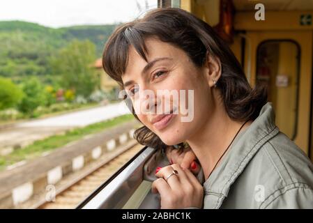 Jeune femme se penchant hors de la fenêtre du train, Bulgarie Banque D'Images