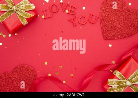 La Saint-Valentin des maquettes. Fond rouge avec des boîtes-cadeaux, rubans et coeurs rouges. Mise à plat d'amour. Banque D'Images