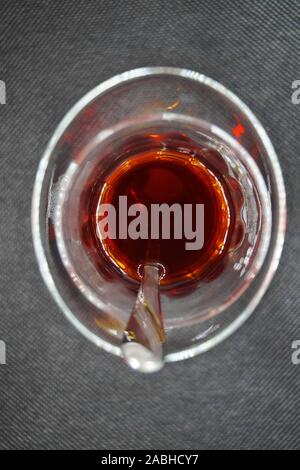 Le thé noir dans un verre avec une cuillère à café Banque D'Images