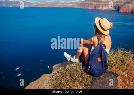 Woman traveler sitting rock à la Caldera depuis à Akrotiri, l'île de Santorin, Grèce. Tourisme, voyages Banque D'Images