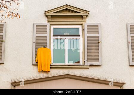 Pull jaune est suspendu à la fenêtre d'une façade de maison Banque D'Images