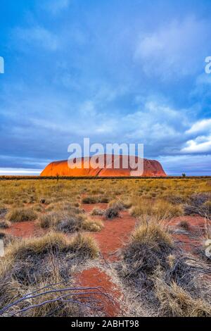 Uluru, aussi connu sous le nom de Ayers Rock, au coucher du soleil avec d'intéressantes formations nuageuses au-dessus. Territoire du Nord, Australie. Banque D'Images