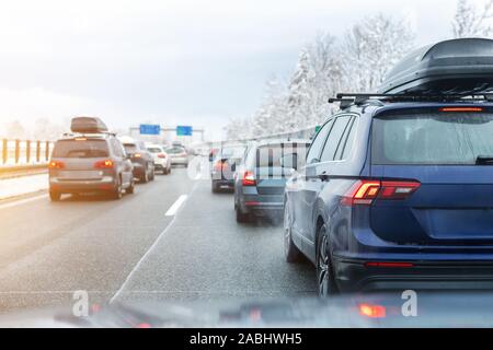 La route d'hiver avec beaucoup de différentes voitures bloqués dans les embouteillages en raison de mauvaises conditions météorologiques. Véhicules sur route mouillée après une tempête de neige et blizzard Banque D'Images