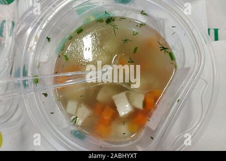 Bouillon de poulet dans un bol en plastique avec une cuillère. La nourriture dans des plats jetables vue d'en haut. Cafe de la restauration rapide. Banque D'Images