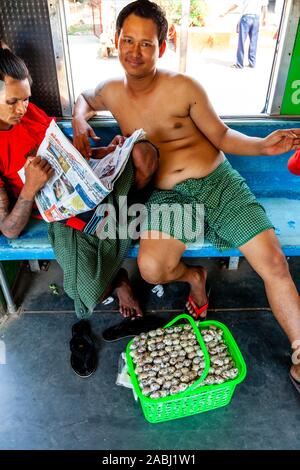 Un snack-vendeur voyageant sur le chemin de fer circulaire de Yangon, Yangon, Myanmar. Banque D'Images