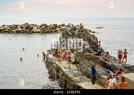 Nager les touristes de la côte rocheuse de la mer Ligure au large du village de Manarola, dans la région des Cinque Terre de l'Italie sous un ciel couvert en fin d'après-midi Banque D'Images