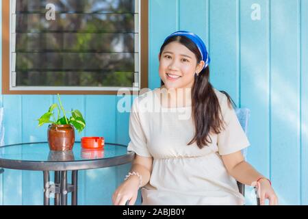 Belle grosse fille grande taille cute teen smiling portrait sourire assis à l'avant home en bois arrière-plan. Banque D'Images