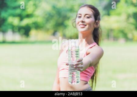 Les femmes sport part indiquent que l'eau potable bouteille pour recommander de boire de l'eau propre pour une bonne santé. Banque D'Images