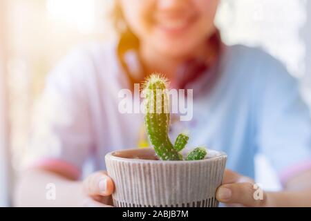 Ado fille sourire heureux avec cactus plante nature vert dans la main. Banque D'Images