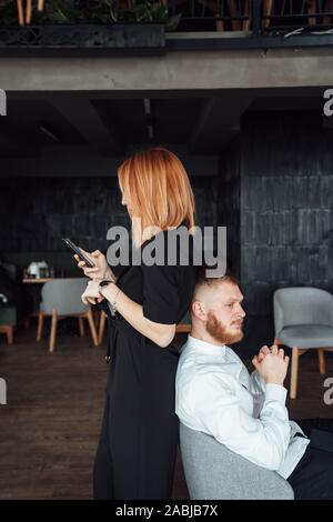 Les jeunes se tenir avec le dos à l'autre avec un smartphones dans les mains. Banque D'Images