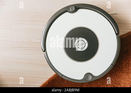 Robot-aspirateur sur le sol de parquet et de nettoyage de tapis. Banque D'Images